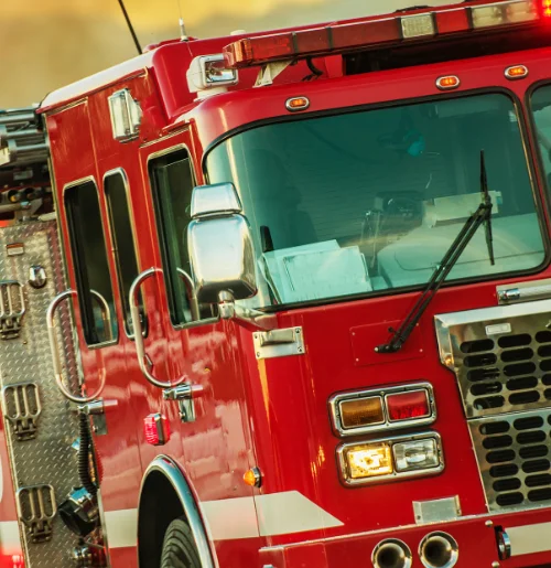 Close-up of a red fire truck, showing the front grille, headlights, and windshield.